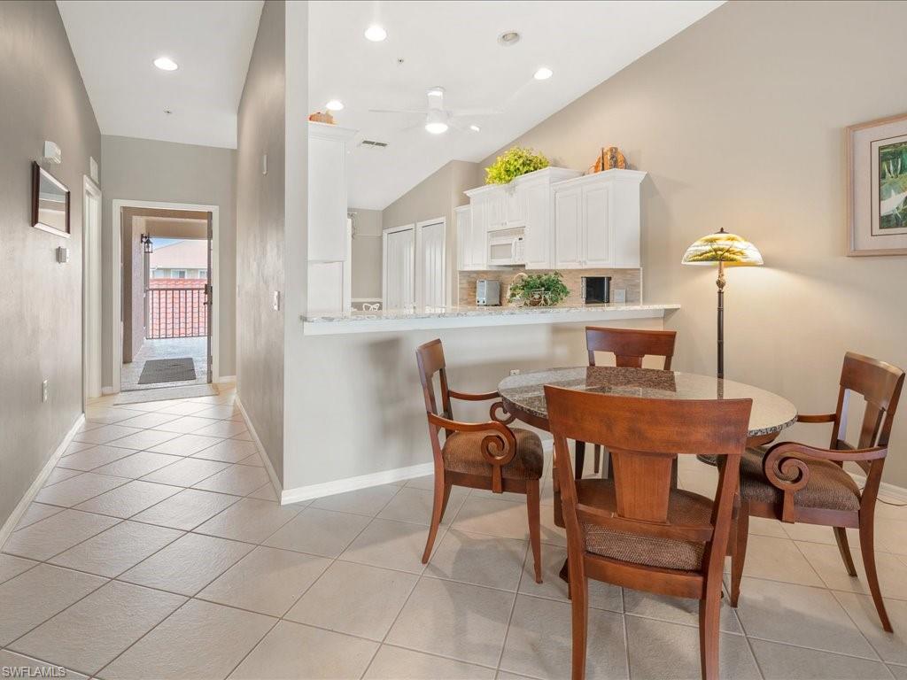 2810 Cypress Trace Circle, Unit 2127 Naples, FL 34119 - Photo 10 of 28 a dining hall with stainless steel appliances a dining table and chairs with kitchen island