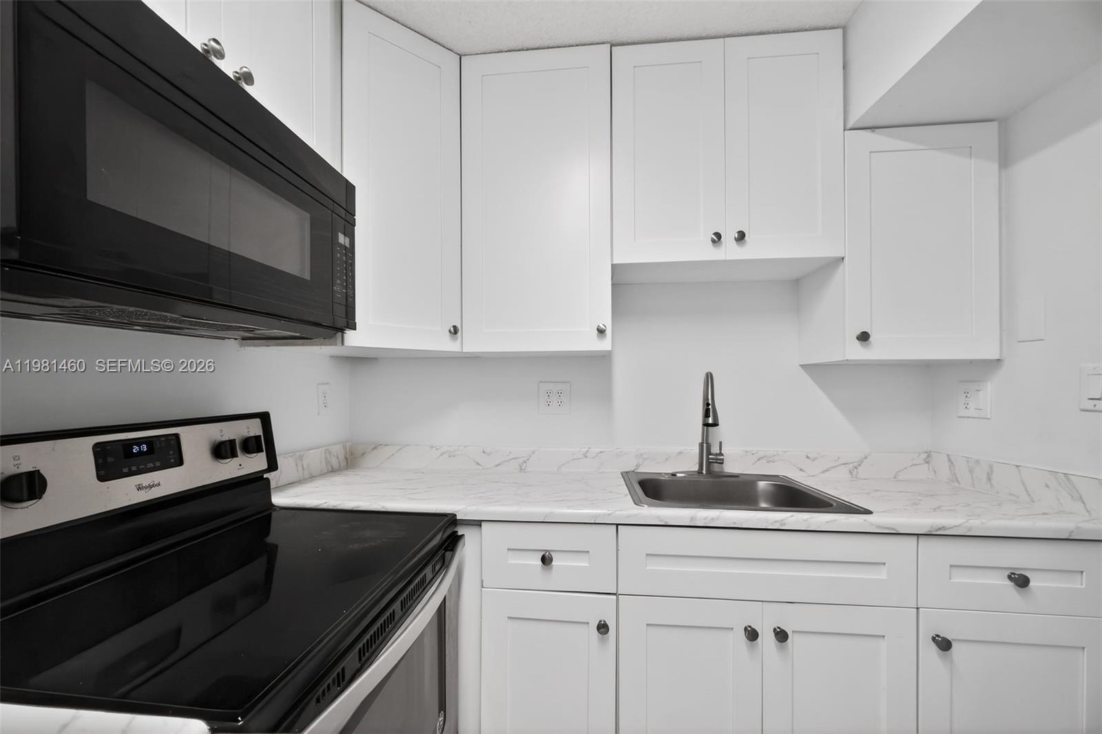 9436 Southwest 140th Court, Unit 9436 Miami, FL 33186 - Photo 12 of 40 a kitchen with white cabinets and black appliances