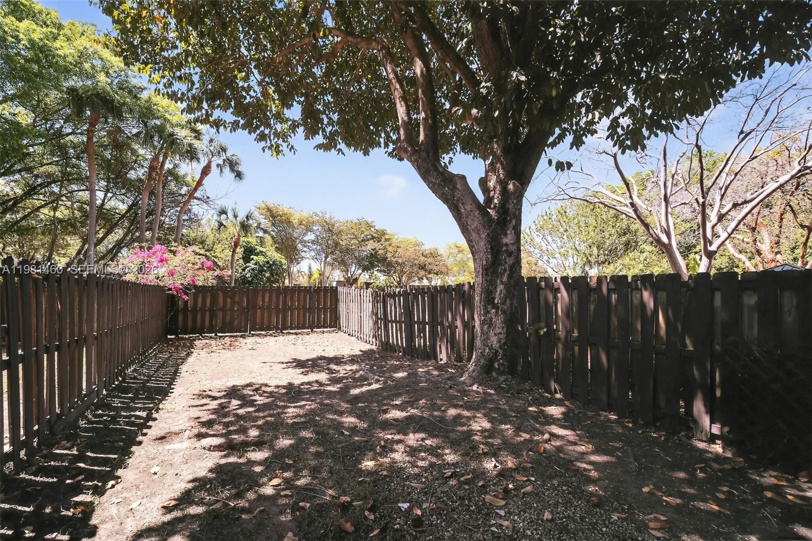 9436 Southwest 140th Court, Unit 9436 Miami, FL 33186 - Photo 34 of 40 a view of backyard with wooden fence and a large tree