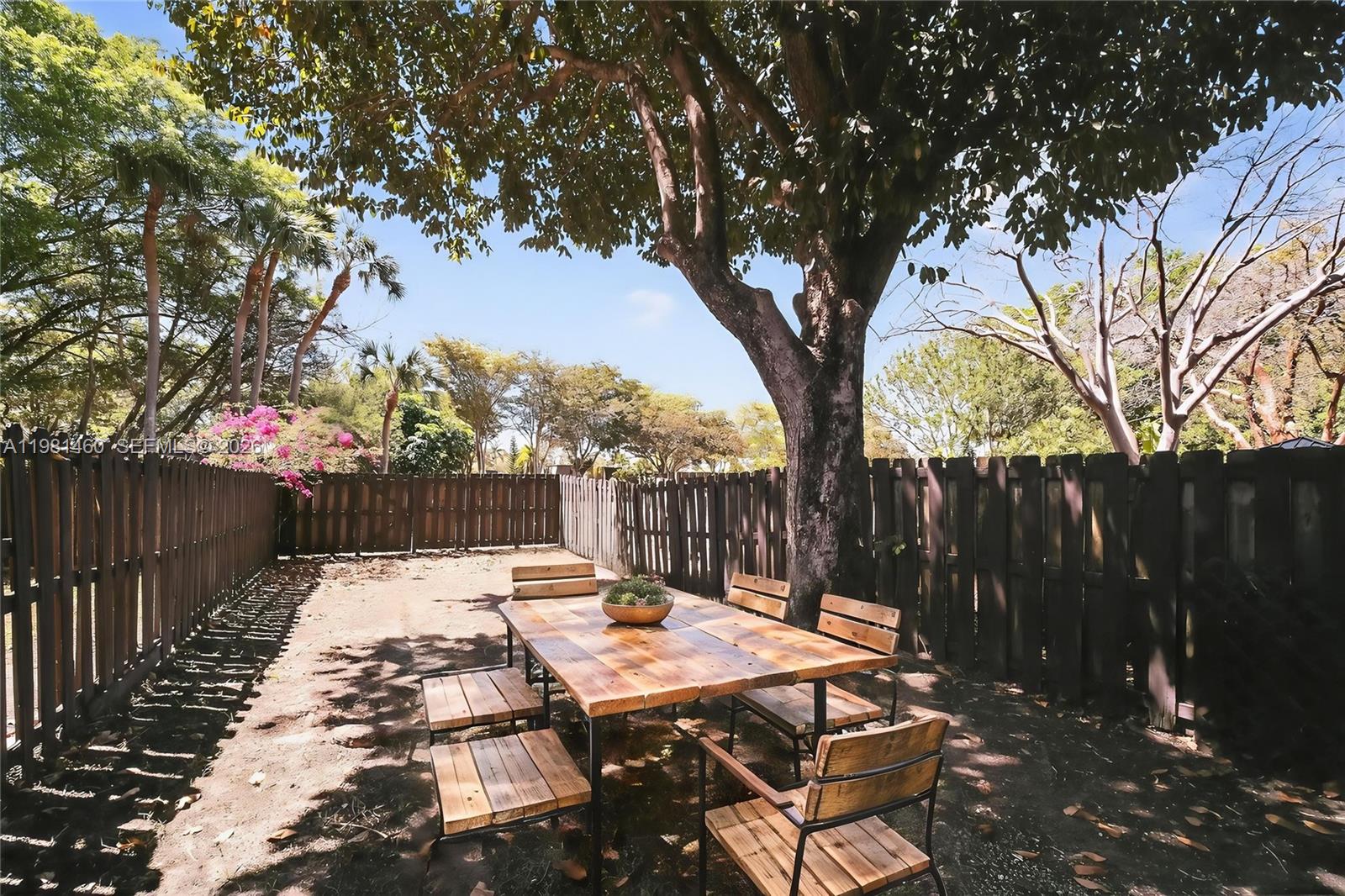 9436 Southwest 140th Court, Unit 9436 Miami, FL 33186 - Photo 5 of 40 a view of a patio with table and chairs with wooden fence and large trees
