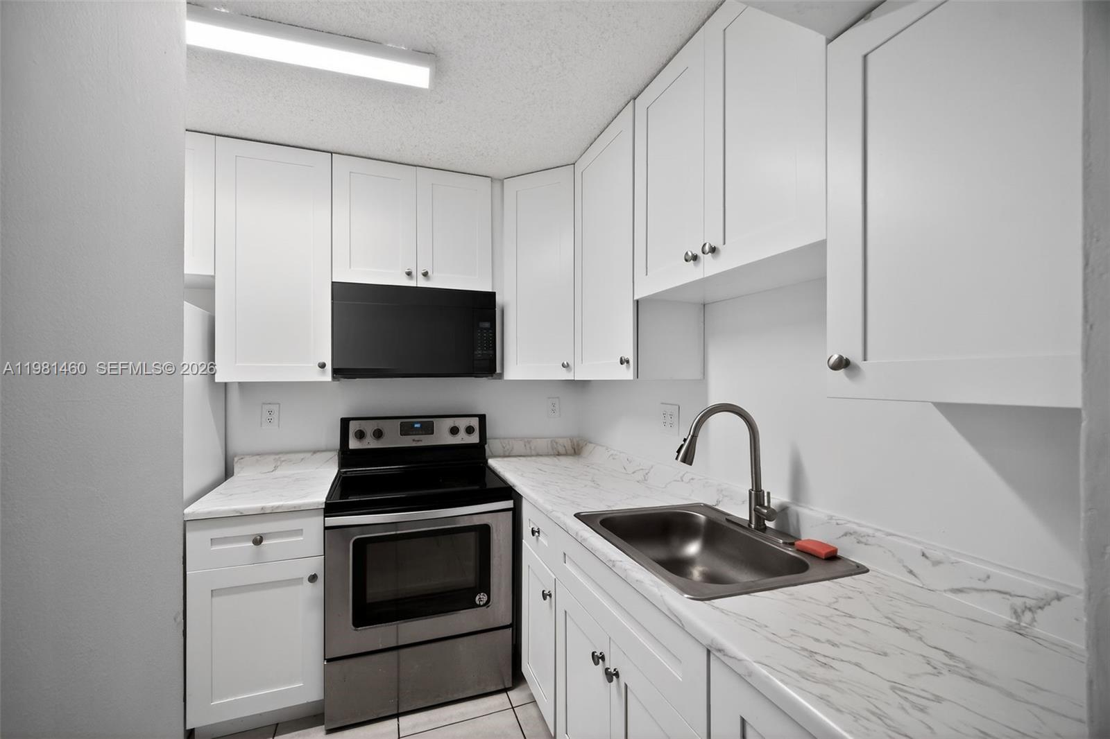 9436 Southwest 140th Court, Unit 9436 Miami, FL 33186 - Photo 10 of 40 a kitchen with granite countertop white cabinets appliances and a sink