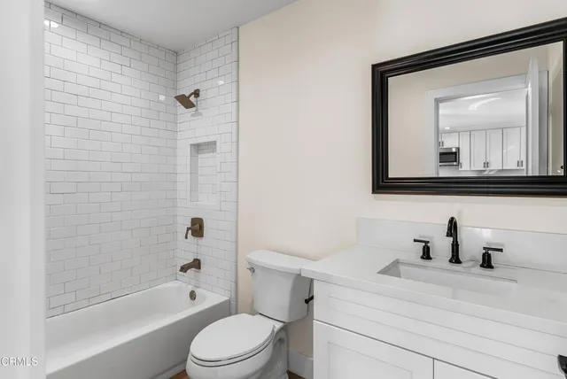 a bathroom with a toilet sink a mirror a bathtub and shower