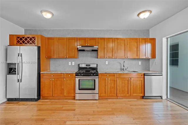 a kitchen with stainless steel appliances granite countertop a stove a sink and a refrigerator