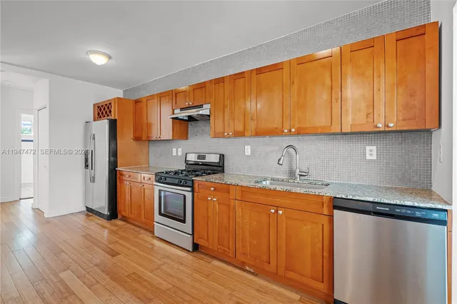 a kitchen with stainless steel appliances granite countertop a stove a sink and a refrigerator