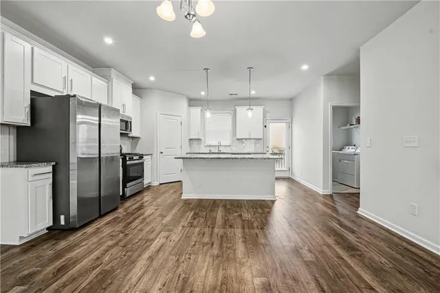 a large kitchen with stainless steel appliances a refrigerator and wooden floor