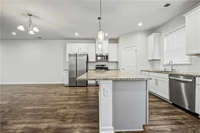a kitchen with kitchen island granite countertop a sink cabinets and stainless steel appliances