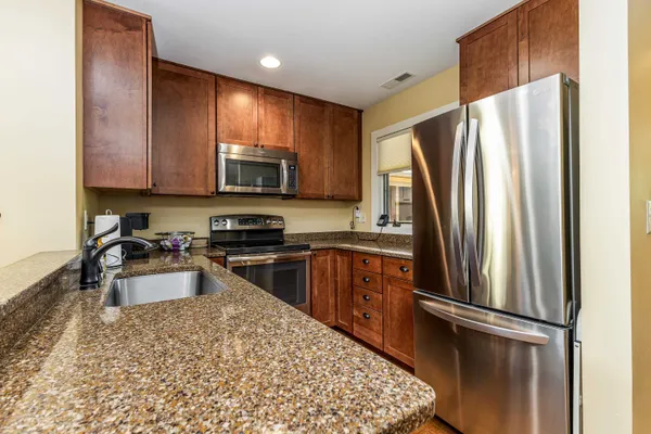 a kitchen with stainless steel appliances granite countertop a stove a sink and a microwave