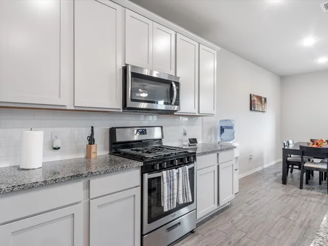 a kitchen with granite countertop cabinets stainless steel appliances and wooden floor