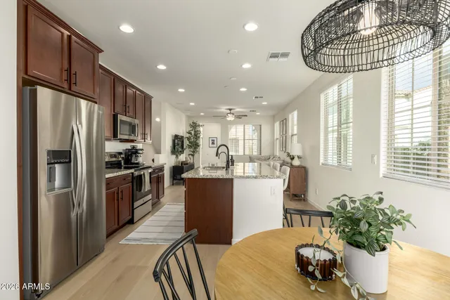 a kitchen with stainless steel appliances granite countertop a refrigerator a sink a stove and chairs