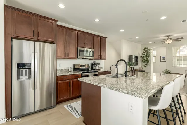 a kitchen with stainless steel appliances granite countertop a refrigerator a sink a stove a dining table and chairs