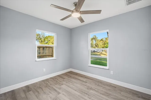 an empty room with windows and fan