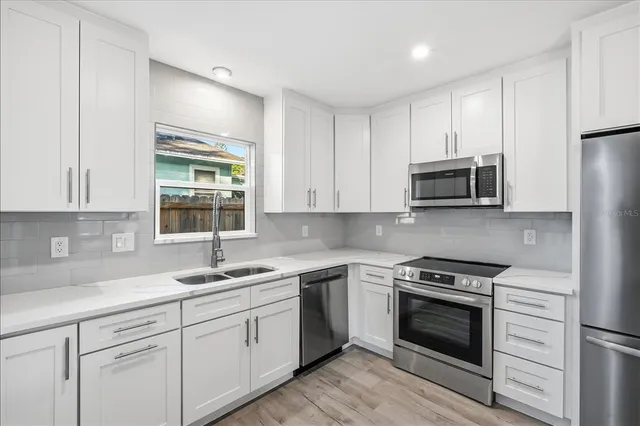 a kitchen with cabinets stainless steel appliances a sink and a window