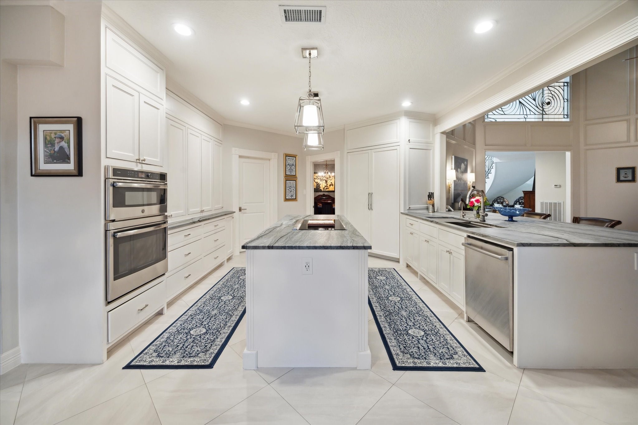 15406 Old Stone Trail Houston, TX 77079 - Photo 14 of 42 This is a spacious, modern kitchen featuring white cabinetry, stainless steel appliances, including a double wall oven, and an island with a sink. The kitchen has tiled flooring, and recessed lighting. It opens up to an adjacent room, giving it an open-concept feel.