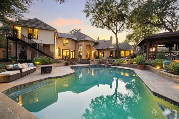 a view of a house with swimming pool and a chairs in patio