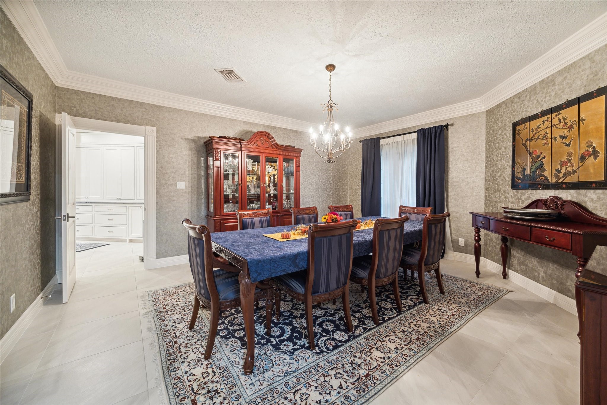 15406 Old Stone Trail Houston, TX 77079 - Photo 8 of 42 This is an elegant dining room featuring textured wallpaper, tile flooring, and is well-lit, with a chandelier and natural light from a window with curtains.