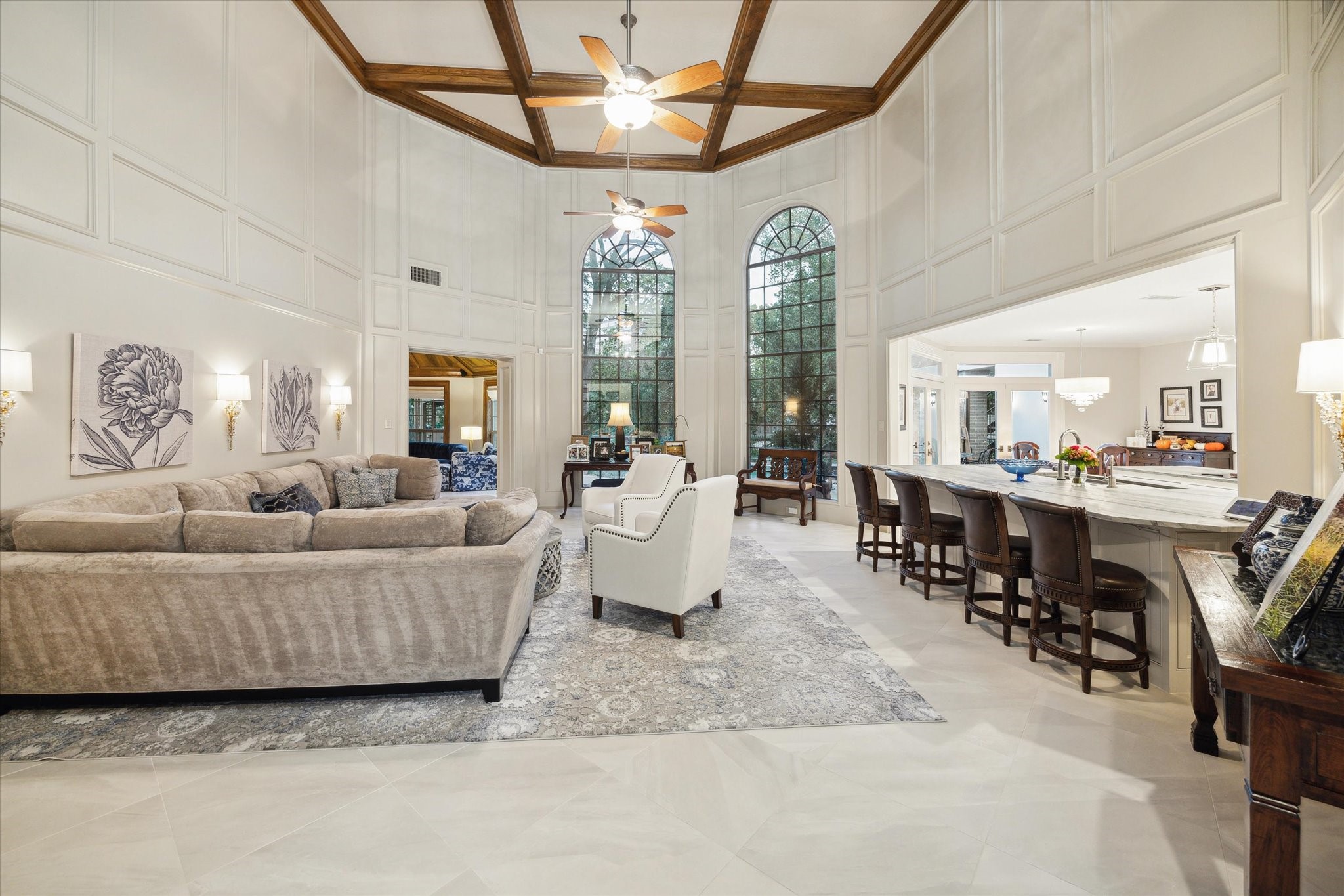 15406 Old Stone Trail Houston, TX 77079 - Photo 41 of 42 This is a spacious, well-lit living space featuring high ceilings with wood beams, large arched windows, an open floor plan connecting to a dining area and kitchen.