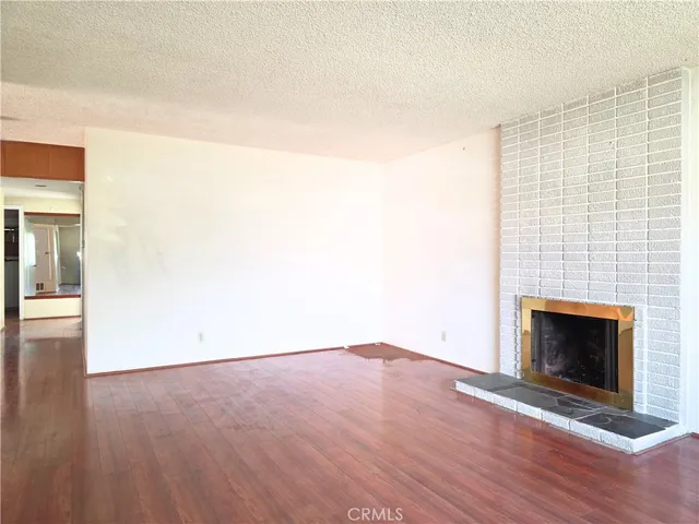 an empty room with wooden floor fireplace and windows