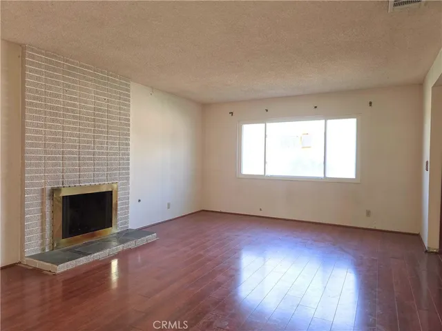 an empty room with wooden floor fireplace and windows