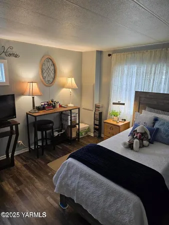 a bedroom with a bed a large window and a potted plant