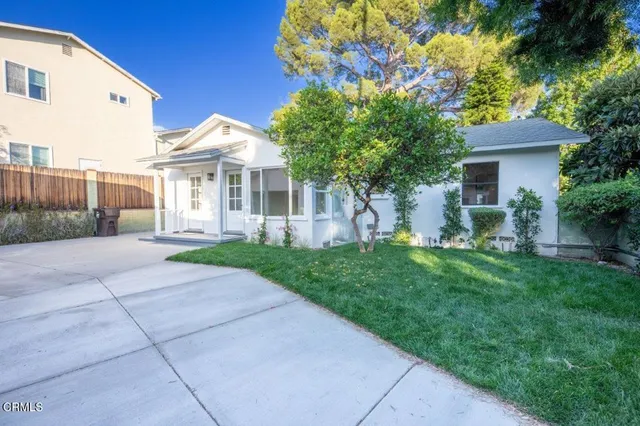 a view of house with a yard and potted plants