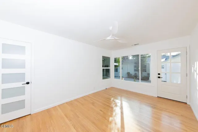 a view of empty room with wooden floor and fan