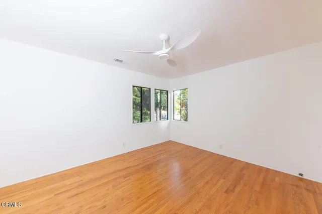 an empty room with a window and ceiling fan