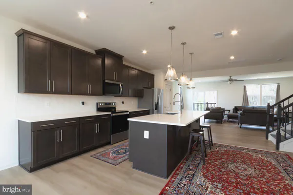 a kitchen with kitchen island a counter top space a sink a refrigerator and wooden floor