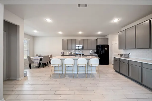a large kitchen with stainless steel appliances kitchen island granite countertop a sink and cabinets