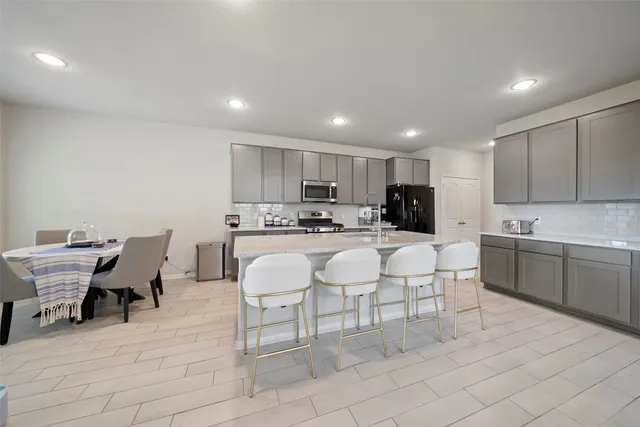 a kitchen with a dining table chairs and white appliances