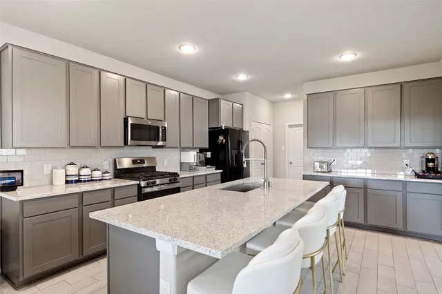 a kitchen with a sink a stove a refrigerator a center island and cabinets