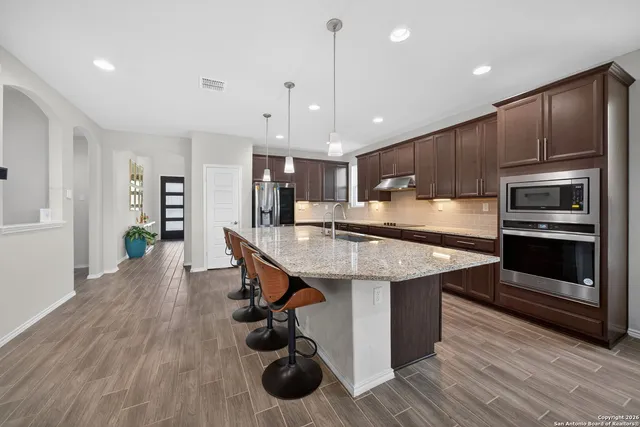 a kitchen with stainless steel appliances a kitchen island hardwood floor sink and stove