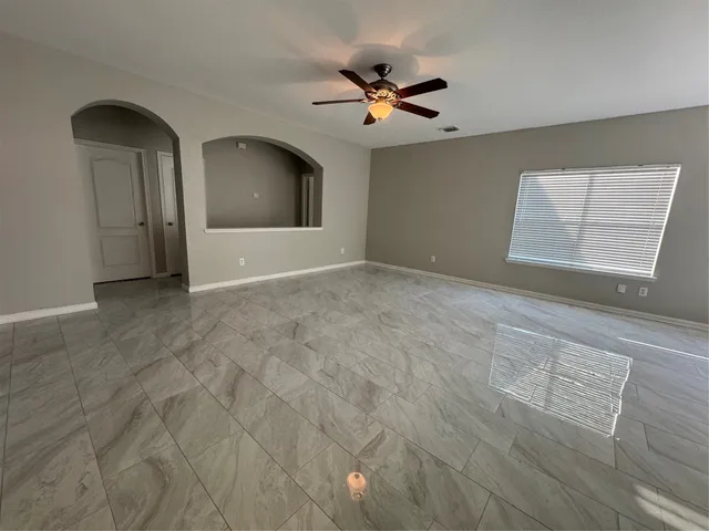 a view of an empty room with a chandelier fan and a window