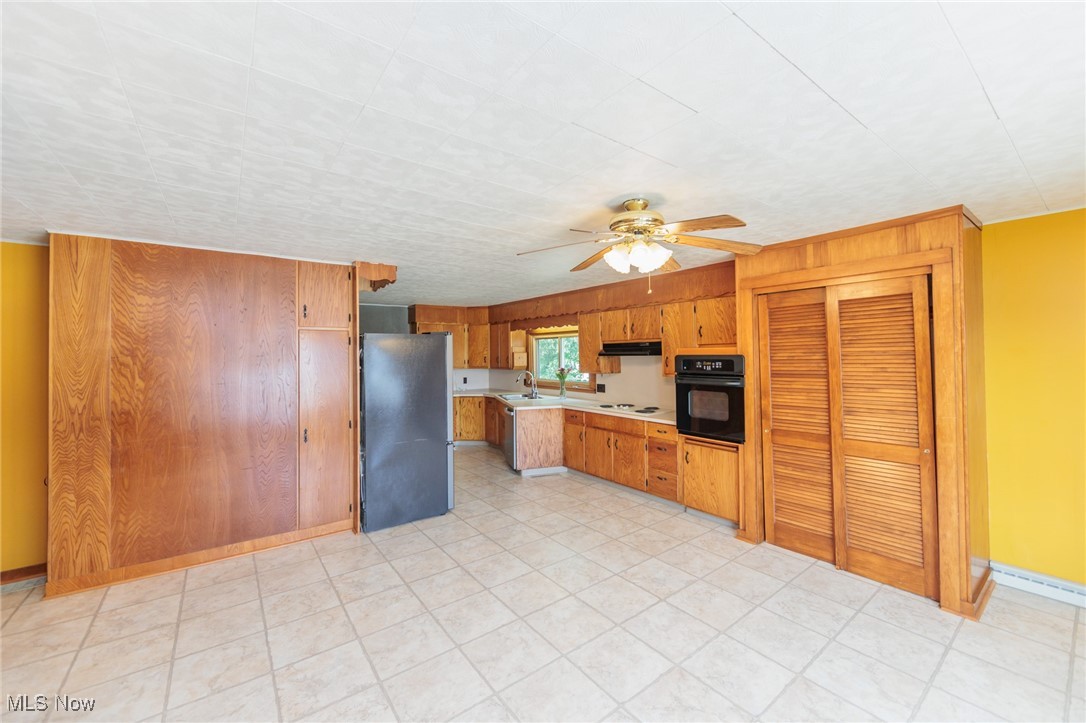 Kitchen featuring stainless steel fridge, oven, sink, white electric stovetop, and ceiling fan