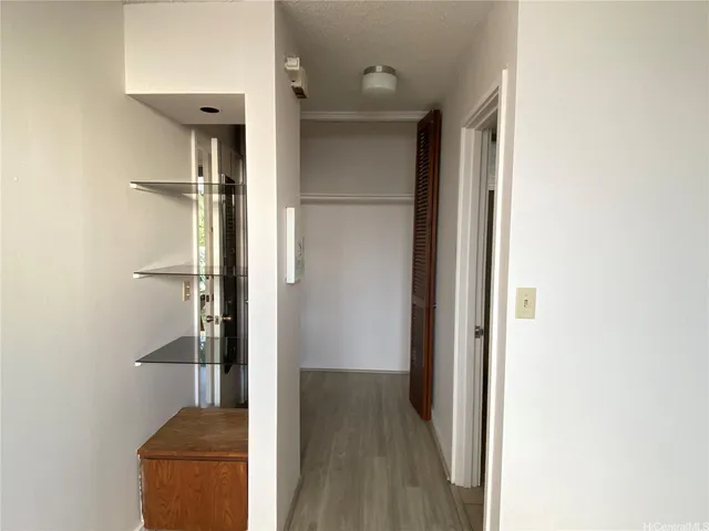 a view of a hallway with wooden floor and closet