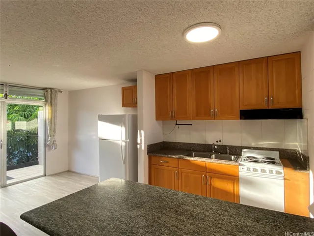 a kitchen with stainless steel appliances granite countertop a stove a sink and a refrigerator