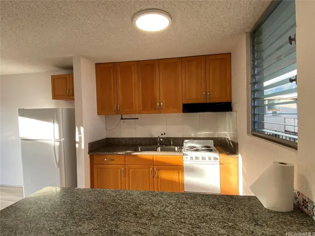 a kitchen with granite countertop a sink a stove and cabinets