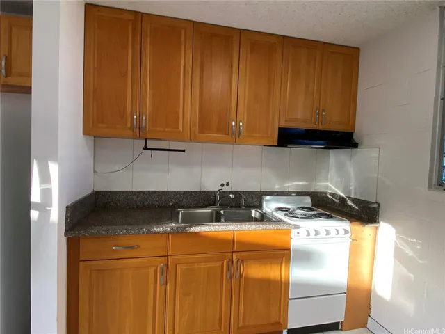 a kitchen with granite countertop a sink a stove and a granite counter top