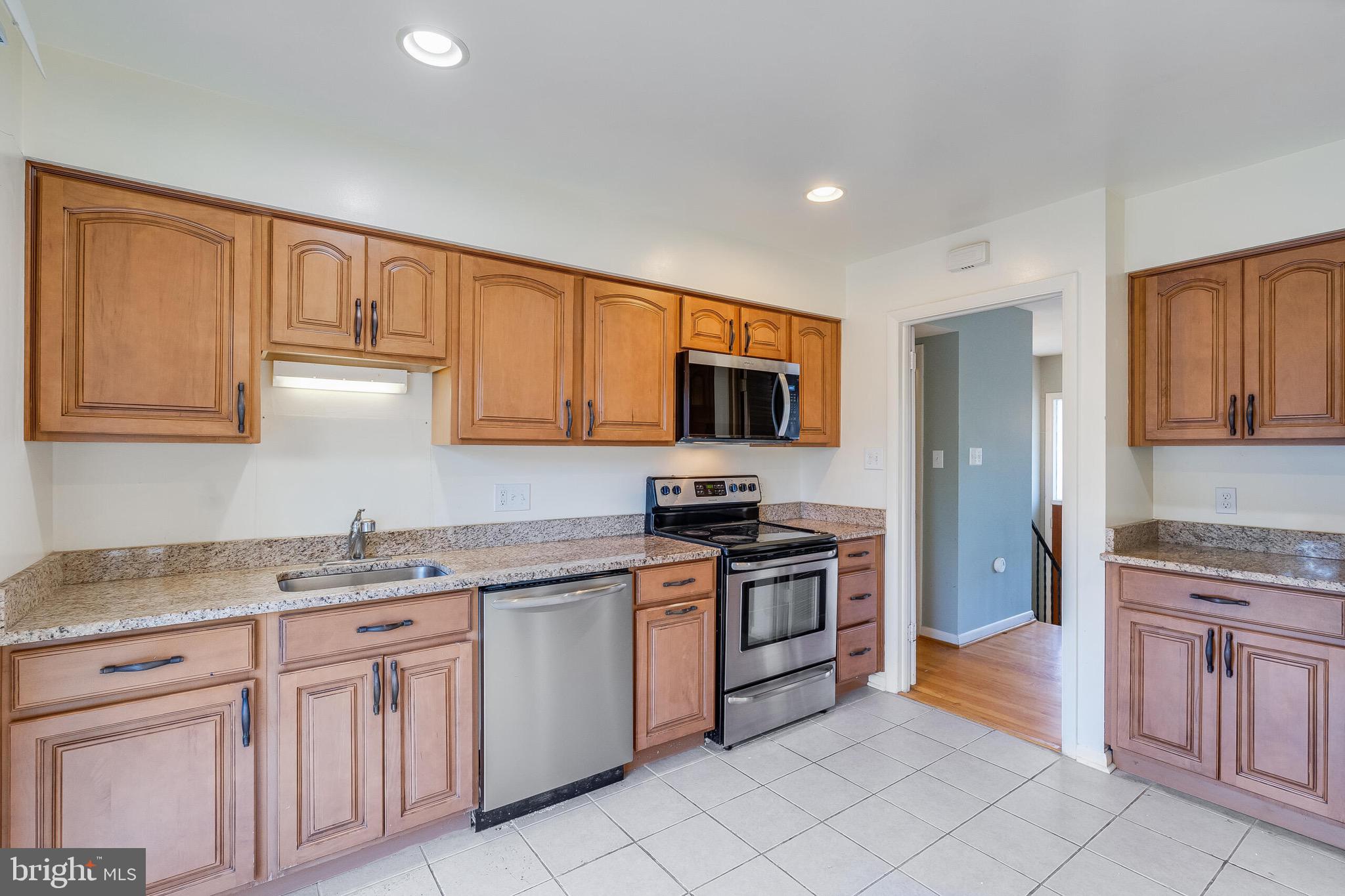 6503 Machodoc Court Falls Church, VA 22043 - Photo 13 of 34 a kitchen with stainless steel appliances granite countertop a stove top oven a sink dishwasher and a refrigerator with wooden cabinets
