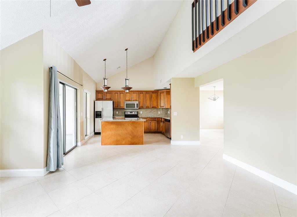 Undisclosed Address Boca Raton, FL 33428 - Photo 12 of 36 a large white kitchen with kitchen island a stove a refrigerator a sink and a dining table