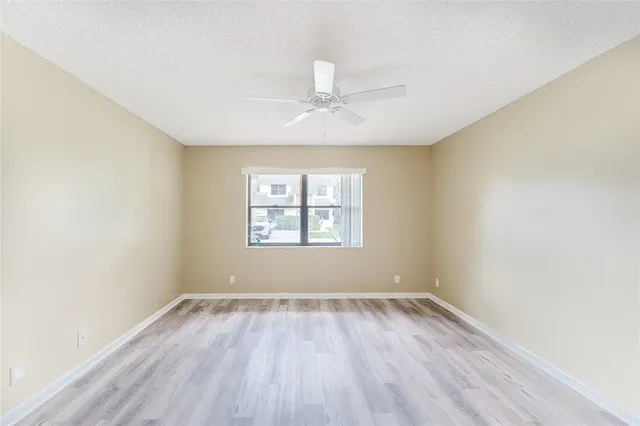 an empty room with wooden floor ceiling fan and windows