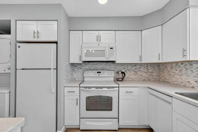 a kitchen with white cabinets and white appliances