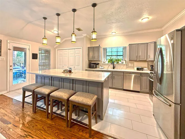 a kitchen with kitchen island a dining table chairs and refrigerator