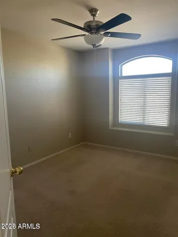 an empty room with a window and a fan