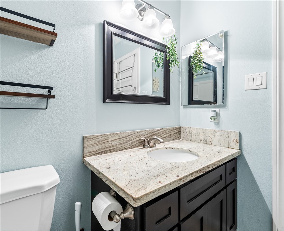 7890 East Spring Street, Unit 22F Long Beach, CA 90815 - Photo 22 of 35 a bathroom with a granite countertop sink a toilet and mirror