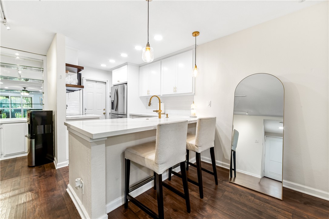 7890 East Spring Street, Unit 22F Long Beach, CA 90815 - Photo 3 of 35 a kitchen with kitchen island a dining table chairs and a wooden floor