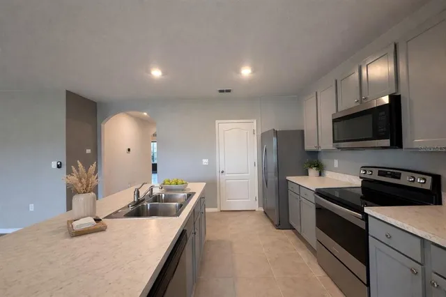 a kitchen with stainless steel appliances a sink a stove a microwave a counter top space and cabinets