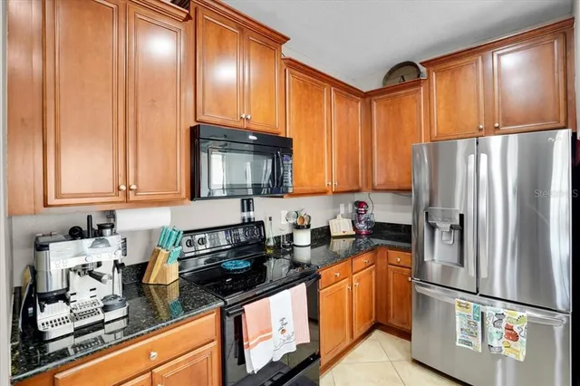 a kitchen with granite countertop stainless steel appliances a refrigerator a sink a stove cabinets and a counter top space