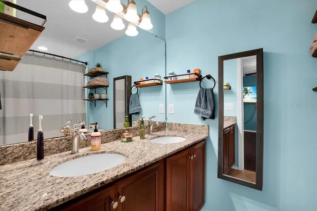 a bathroom with a granite countertop sink and a mirror