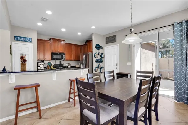 a kitchen with a dining table chairs and refrigerator