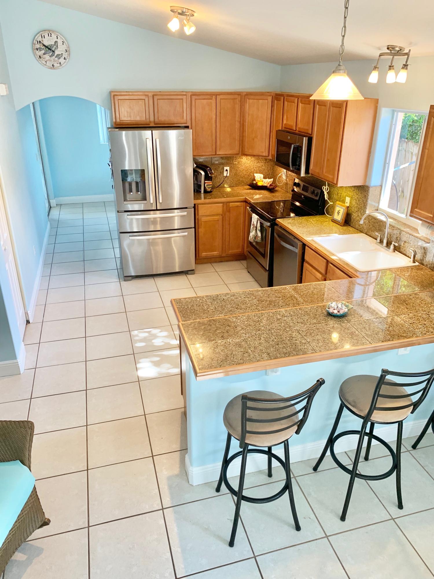 46 Snapper Avenue Key Largo, FL 33037 - Photo 3 of 26 a kitchen with stainless steel appliances kitchen island granite countertop a table chairs and a refrigerator